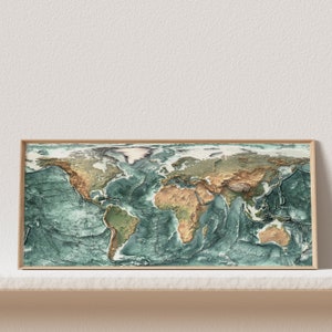 May include: A framed world map print with a raised relief design. The map is in shades of green and brown, with the oceans depicted in a darker shade of green. The frame is a light wood color.
