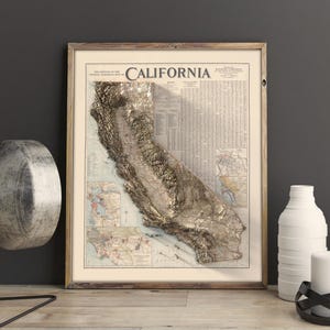 K&ouml;nnte beinhalten: Eine gerahmte Vintage-Karte von Kalifornien mit einem 3D-Pr&auml;geeffekt, der die Topographie des Staates in Gold zeigt. Die Karte tr&auml;gt den Titel "California" und enth&auml;lt detaillierte Informationen &uuml;ber die Geographie des Staates.