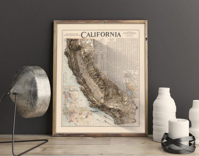 K&ouml;nnte beinhalten: Eine gerahmte Vintage-Karte von Kalifornien mit einem 3D-Pr&auml;geeffekt, der die Topographie des Staates in Gold zeigt. Die Karte tr&auml;gt den Titel "California" und enth&auml;lt detaillierte Informationen &uuml;ber die Geographie des Staates.