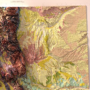 May include: A detailed topographic map of a region, featuring a variety of colors to represent different elevations and geological features. The map shows mountainous terrain in shades of brown and red, transitioning to flatter areas in yellow and green.