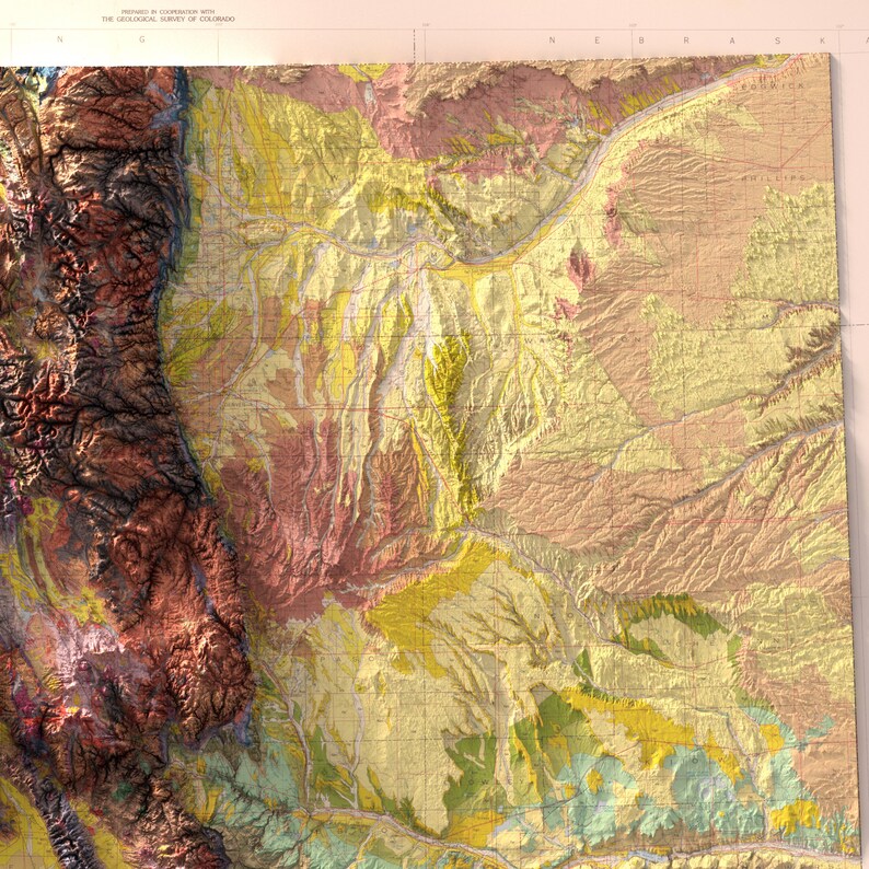 May include: A detailed topographic map of a region, featuring a variety of colors to represent different elevations and geological features. The map shows mountainous terrain in shades of brown and red, transitioning to flatter areas in yellow and green.