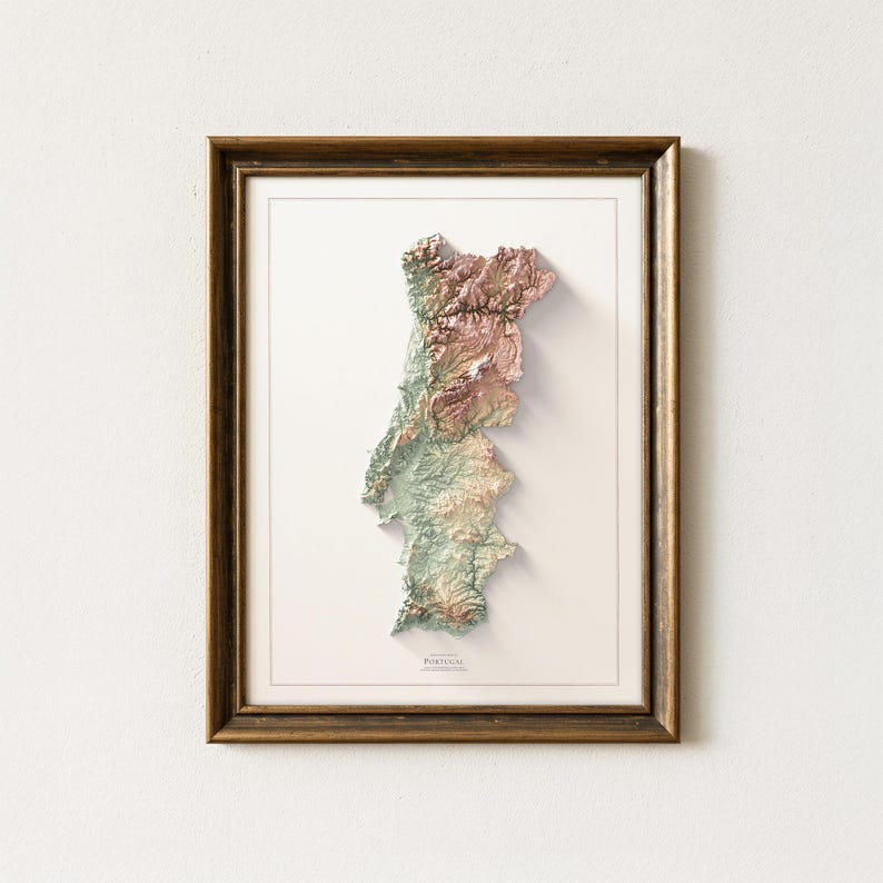 May include: Framed 3D relief map of Portugal, showcasing the country's topography in shades of green, brown, and pink. The map is set against a white background within a dark brown wooden frame. The word "PORTUGAL" is printed at the bottom.