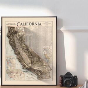 K&ouml;nnte beinhalten: Eine Vintage-Karte von Kalifornien mit einem 3D-Pr&auml;geeffekt. Die Karte ist auf cremefarbenem Papier gedruckt und in einem schwarzen Rahmen gerahmt. Der Titel "CALIFORNIA" ist in einer fetten Serifenschrift oben auf der Karte gedruckt.