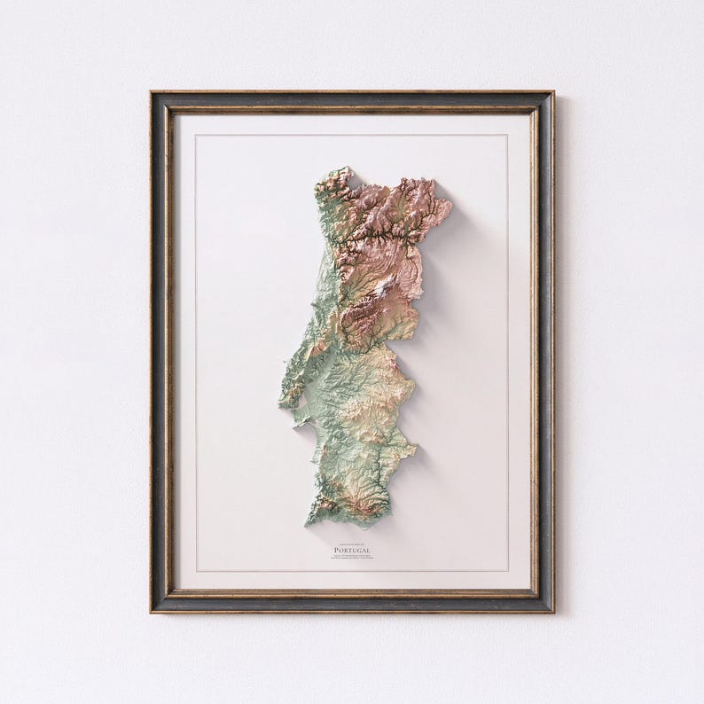 May include: Framed 3D relief map of Portugal, showcasing the country's topography in shades of green, brown, and pink. The map is set against a white background, framed in a dark wood frame.