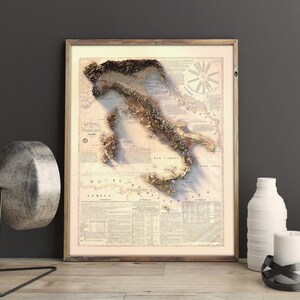 May include: A vintage-style map of Italy with a 3D embossed effect. The map is printed on a cream-colored paper with brown text and details. The map is framed in a light brown wood frame.