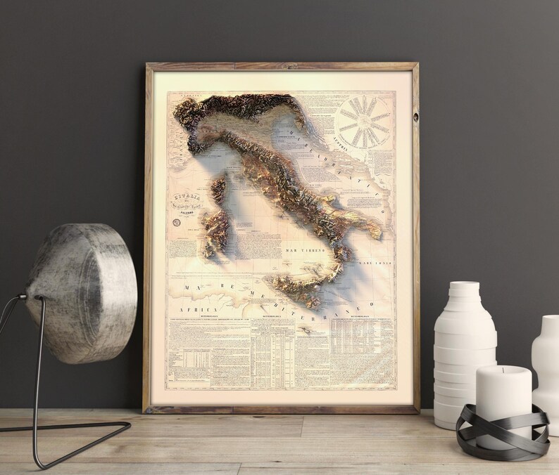 May include: A vintage-style map of Italy with a 3D embossed effect. The map is printed on a cream-colored paper with brown text and details. The map is framed in a light brown wood frame.