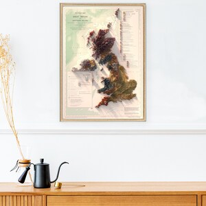 May include: A vintage-style, framed map of Great Britain and Northern Ireland. The map is a relief map, showing the topography of the islands in a 3D style. The map is printed in shades of brown, green, and red, with a key to the different geological formations.