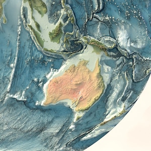 May include: A physical relief map of the Earth featuring a textured, three-dimensional representation of the Australian continent in shades of tan and orange, surrounded by deep blue ocean basins with visible underwater topography and ridges.