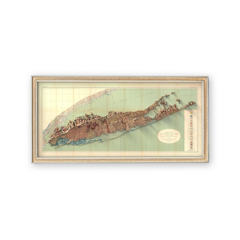 May include: A vintage, framed map of Long Island, New York, with a 3D relief effect. The map is printed on a light green background with brown, red, and yellow details. The map is framed in a light brown frame.