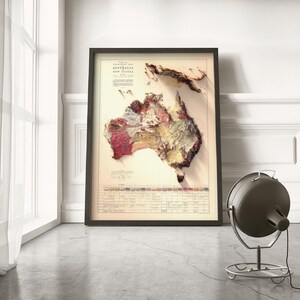 May include: A vintage-style relief map of Australia and New Guinea, printed on paper and framed in black. The map shows the terrain in shades of brown, red, and yellow.