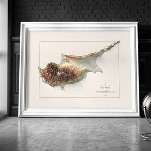 May include: A framed 3D topographic map of Cyprus, showing the island's terrain in shades of green, brown, and beige. The map is titled "Cyprus" and is surrounded by a white frame.