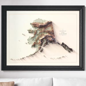 May include: Framed elevation map of Alaska, featuring a 3D topographic representation in shades of brown, green, and white. The map is set against a cream background, enclosed in a black frame. The text "Elevation Map Alaska" is visible.