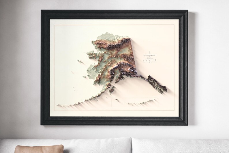 May include: Framed elevation map of Alaska, featuring a 3D topographic representation in shades of brown, green, and white. The map is set against a cream background, enclosed in a black frame. The text "Elevation Map Alaska" is visible.
