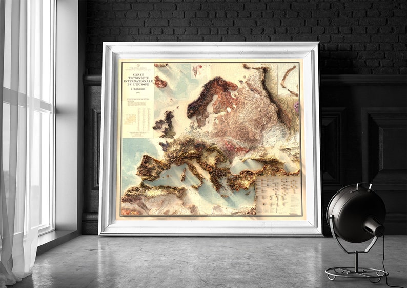 Pu&ograve; includere: Una mappa vintage, dettagliata e in rilievo dell'Europa con uno sfondo blu chiaro e accenti dorati. La mappa &egrave; intitolata "Carte Orographique Internationale de L'Europe" e include una tabella di altezze.