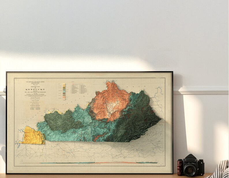 May include: A vintage, detailed relief map of Kentucky, showing the state's topography with different colors representing elevation. The map is framed in black and has a white background.