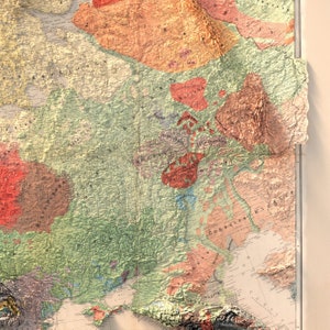 Op de afbeelding: Een vintage kaart van Europa met de nadruk op Oost-Europa. De kaart is gedrukt op papier en heeft een textuur, een verhoogd oppervlak. De kaart is gekleurd in tinten groen, bruin en rood en bevat tekstlabels in het Duits.