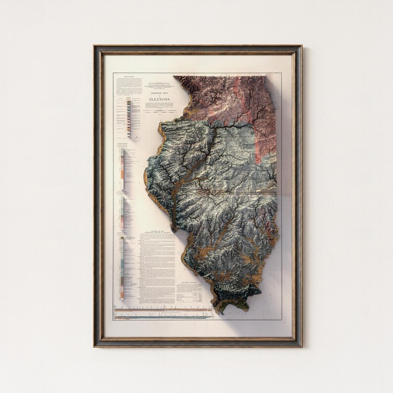 May include: Framed 3D topographic map of Illinois, showcasing the state's terrain with detailed relief. The map features a color palette of greens, browns, and blues, with a key and text along the left side. The map is encased in a wooden frame.