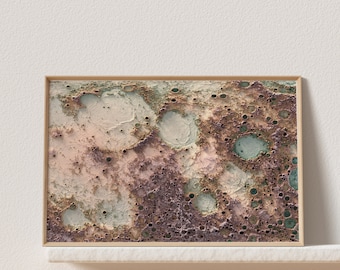 May include: A framed abstract print featuring a textured, cratered surface in shades of brown, pink, and green. The print has a modern, minimalist aesthetic.