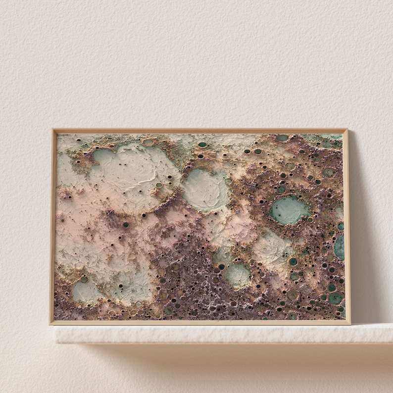 May include: A framed abstract print with a textured, cratered surface in shades of brown, pink, and green. The print has a modern, minimalist aesthetic.