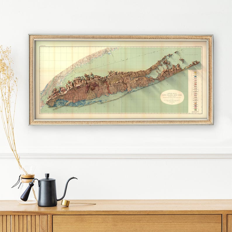 May include: A vintage map of Long Island, New York, in a gold frame. The map is a relief map, showing the topography of the island. The map is printed on a light green background with brown and blue details.