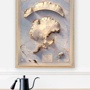 May include: A framed vintage map of Antarctica with a 3D relief effect. The map is in shades of blue, brown, and white, and features the continent's coastline, mountains, and glaciers. The map is titled "ANTARCTICA" and includes a compass rose and a scale bar.