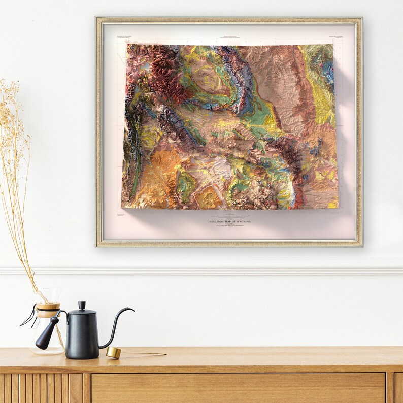 Puede incluir: Un mapa geol&oacute;gico enmarcado de Wyoming con un efecto 3D. El mapa est&aacute; impreso en varios colores, incluyendo tonos de rojo, naranja, amarillo, verde y azul. El mapa est&aacute; titulado "GEOLOGIC MAP OF WYOMING".