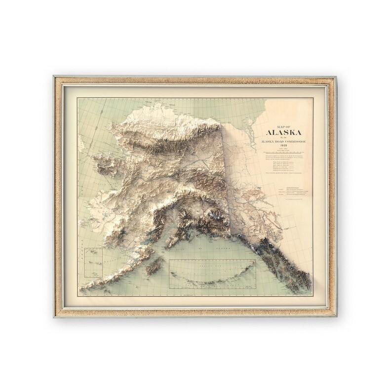 Alaska 3D topographic map art in a reclaimed wood frame, hanging above a stone fireplace in a cozy log cabin. Surrounded by antler decor, a wool throw blanket, and vintage hiking boots, this vintage-style print captures Denali’s peaks and Bristol Bay’s rivers—ideal for adventure lovers seeking rugged wilderness decor or a nostalgic gift for Alaska road trip memories.