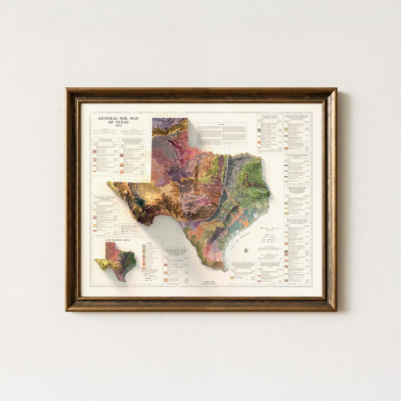 Op de afbeelding: Ingelijste kaart van Texas, met een gedetailleerde bodemkaart met diverse kleuren die verschillende bodemtypen vertegenwoordigen. De kaart zit in een bruine houten lijst. De titel "GENERAL SOIL MAP OF TEXAS" is zichtbaar.