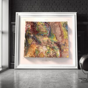 Puede incluir: Un mapa topogr&aacute;fico enmarcado de Wyoming, que muestra el terreno diverso del estado en tonos de marr&oacute;n, verde, azul y amarillo. El mapa est&aacute; titulado "Topographic Map of Wyoming" e incluye un aviso de copyright.