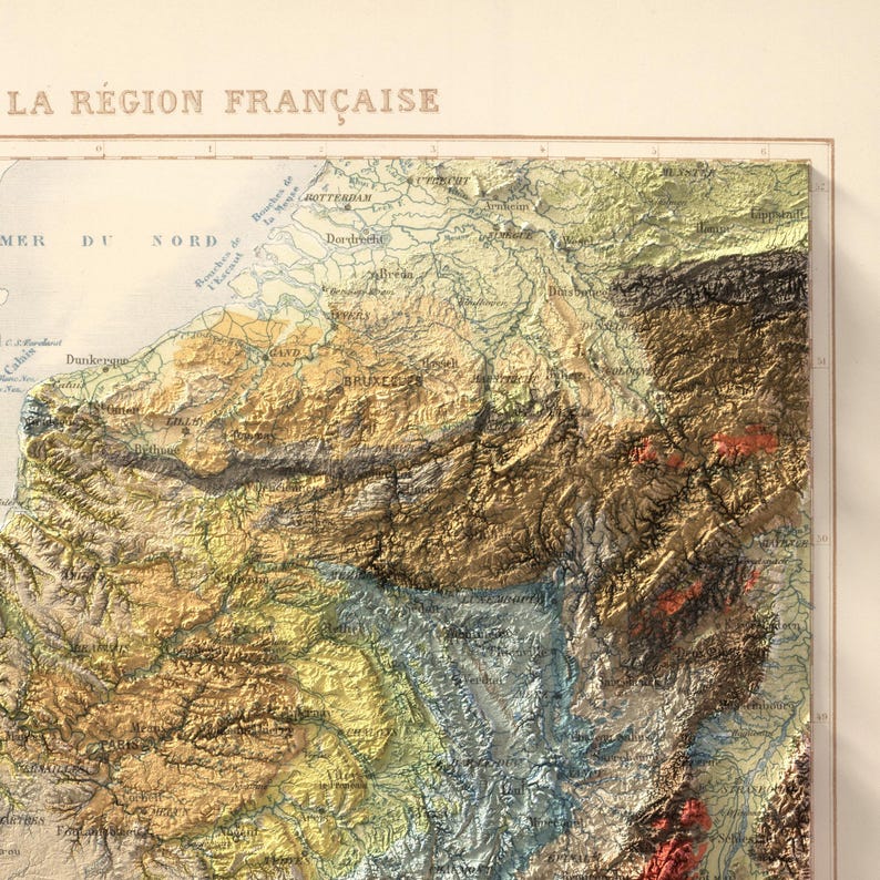 May include: A detailed, vintage relief map of a region in France, featuring textured terrain in shades of brown, green, and yellow. The map includes place names and is labeled "LA R&Eacute;GION FRAN&Ccedil;AISE" at the top. The map is framed.