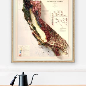 May include: A framed vintage geologic map of California, with a 3D relief effect. The map shows a detailed, colour-coded representation of the state's geological features, framed in a gold-coloured frame. The text "GEOLOGIC MAP OF CALIFORNIA" is visible.