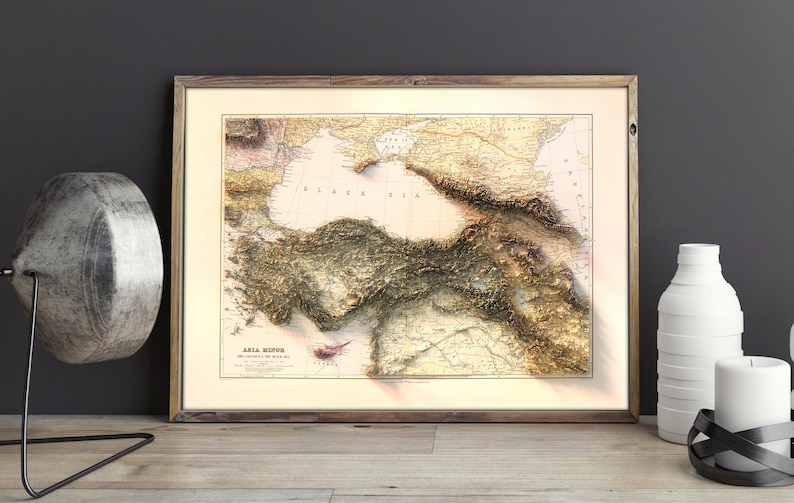 May include: A vintage map of Asia Minor, showing the topography of the region with detailed lines and shading. The map is framed in a wooden frame and has a light beige background.