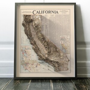 K&ouml;nnte beinhalten: Eine Vintage-Karte von Kalifornien mit einem 3D-Relief-Effekt. Die Karte ist in einem schwarzen Rahmen gerahmt und hat einen wei&szlig;en Hintergrund. Der Titel "California" ist in gro&szlig;en, fetten Buchstaben oben auf der Karte gedruckt.