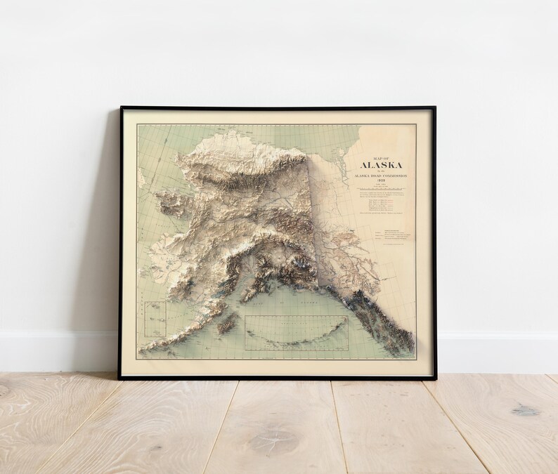 Alaska-British Columbia border map in a navy-blue frame, styled in a seaside cottage with rope accents, driftwood, and a model sailboat. The artwork showcases the Malespina Glacier and coastal fjords, blending nautical charm with topographic precision—ideal for Pacific Northwest travelers, marine biology enthusiasts, or as a unique wedding gift for coastal theme lovers.