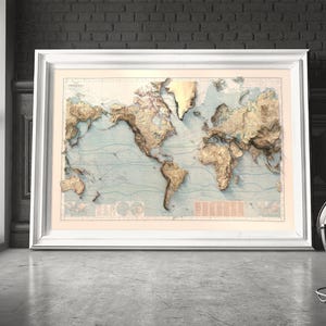 May include: A large, framed world map print featuring a relief-style design with raised-looking golden landmasses set against a pale blue ocean background. The map includes detailed topographical shading, thin contour lines, and a white frame.