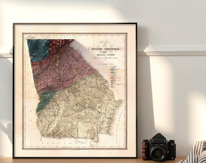 May include: A vintage map of the State of Georgia, showing geological features. The map is printed in black and white with colored lines and text. The map is framed in a black frame.