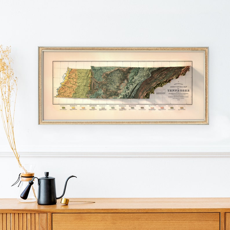 May include: A framed vintage map of Tennessee with a relief style depiction of the state's topography. The map is printed in shades of green, brown, and yellow, with a key showing the different geological formations. The title "Topographical Map of Tennessee" is printed at the bottom of the map.
