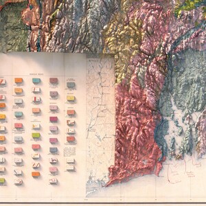 May include: A vintage geological map of New England, showing the different types of rocks and formations in the region. The map is color-coded, with each color representing a different type of rock. The map also includes a legend that explains the different colors and their corresponding rock types.