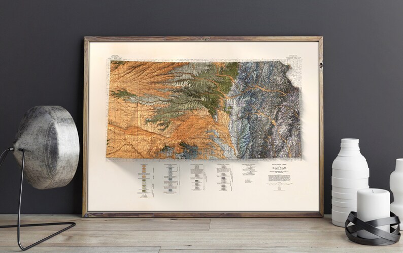 Puede incluir: Un mapa topogr&aacute;fico vintage del estado de Kansas, impreso en colores marr&oacute;n, verde y azul. El mapa est&aacute; enmarcado en un marco de madera y est&aacute; colgado en una pared.