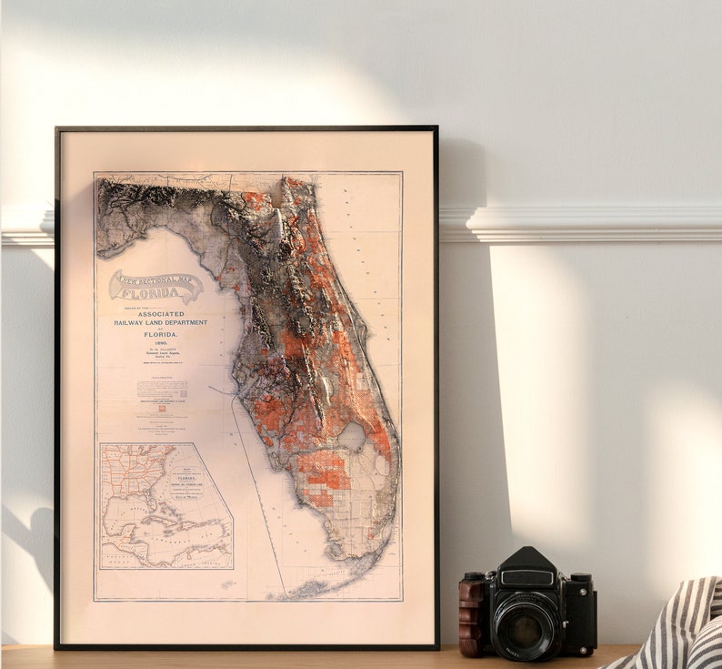 May include: An antique map of Florida, printed in black and white with red and orange accents. The map shows the state's topography and is titled "The State of Florida, Associated Railway Land Department, Florida, 1905."