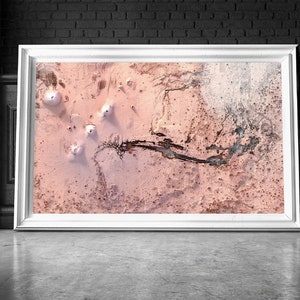 May include: An aerial photograph of a pink and white landscape with a winding black line through the centre. The landscape is covered in small, white mounds.