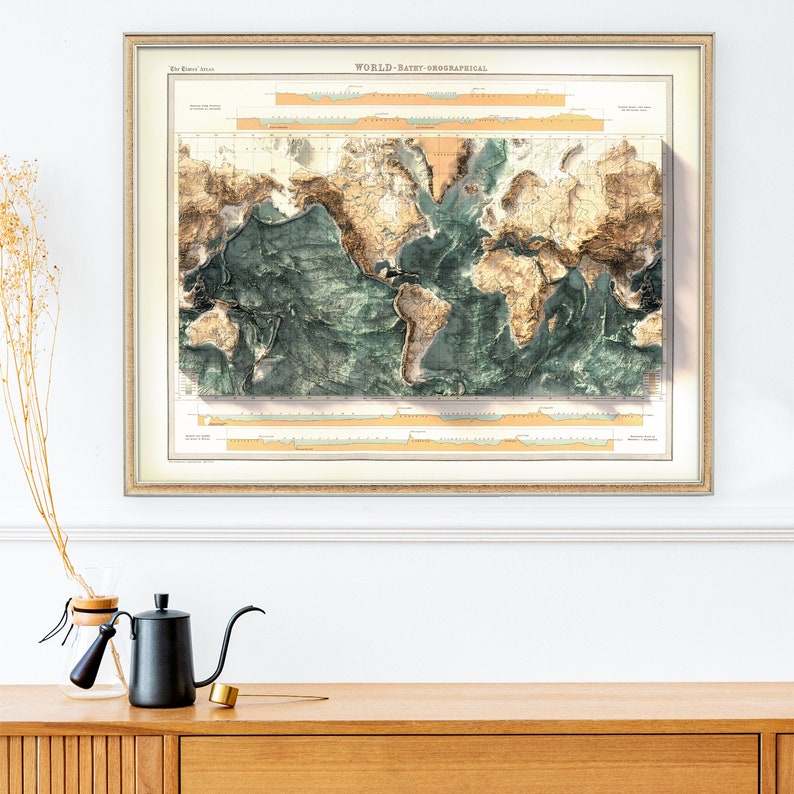 Pu&ograve; includere: Mappa del mondo vintage incorniciata con design batimetrico. Le masse terrestri sono marroni, gli oceani verde-azzurri, con effetto rilievo. La cornice &egrave; in legno chiaro, esposta su una parete bianca sopra un mobile in legno. Etichetta: 'WORLD - BATHY-OROGRAPHICAL'.