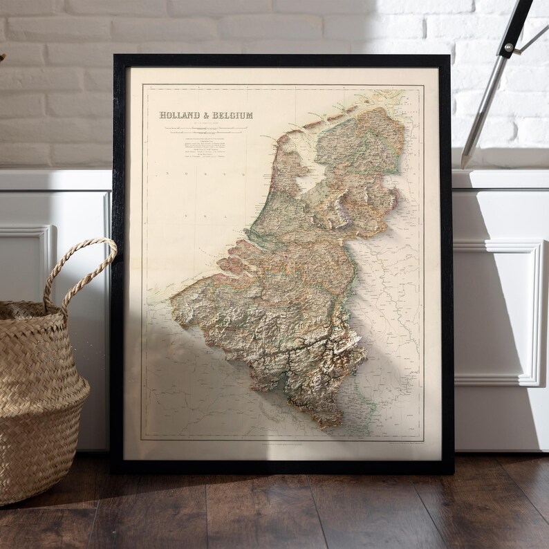 Pode incluir: Um mapa vintage da Holanda e da B&eacute;lgica, impresso em preto e branco com acentos marrons e verdes. O mapa mostra a topografia da regi&atilde;o com linhas e sombreamento detalhados.