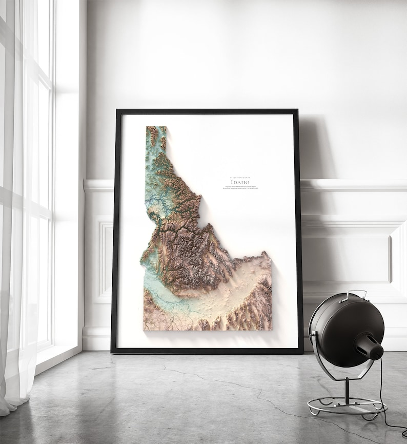 May include: A framed topographic map of the state of Idaho, with a black frame and a white background. The map is in shades of brown, green, and blue, showing the state's terrain.