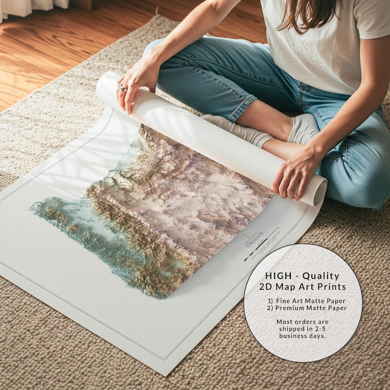 Puede incluir: Una persona desenrolla una impresi&oacute;n art&iacute;stica de mapa 2D de Oreg&oacute;n. El mapa presenta un dise&ntilde;o topogr&aacute;fico detallado en tonos marrones, beige y azules. La impresi&oacute;n es sobre papel mate blanco. El texto en la impresi&oacute;n dice "HIGH - Quality 2D Map Art Prints".