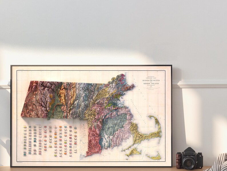 May include: A vintage map of Massachusetts and Rhode Island, showing the terrain in different colors. The map is framed in black and has a white background.