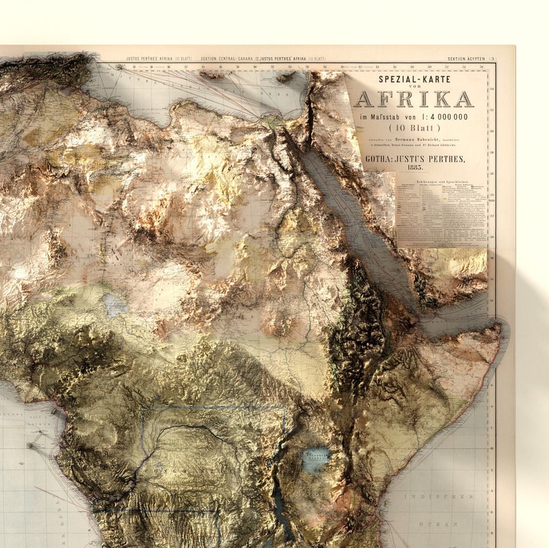 May include: A vintage map of Africa with a 3D relief effect, showing the continent's topography. The map is titled "Speziall-Karte von Afrika" and is dated 1885. The map is printed on paper and has a light brown color.
