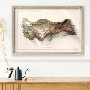 May include: A framed map of Turkey with a 3D relief design. The map is printed on a cream-colored paper with a light brown frame. The title of the map is "T&uuml;rkiye Y&uuml;ksekli Haritası" in Turkish.