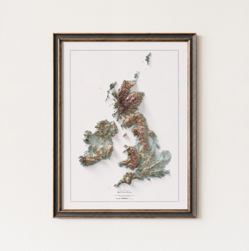 May include: Framed topographic map of the British Isles, featuring detailed relief shading in shades of brown, green, and blue. The map is set against a white background and enclosed in a dark brown frame. The title "British Isles" is visible at the bottom.