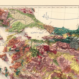 May include: A vintage map of a mountainous region with a coastline. The map is in shades of green, brown, and red, with some blue lines indicating rivers or streams. The map is labelled in Arabic script.